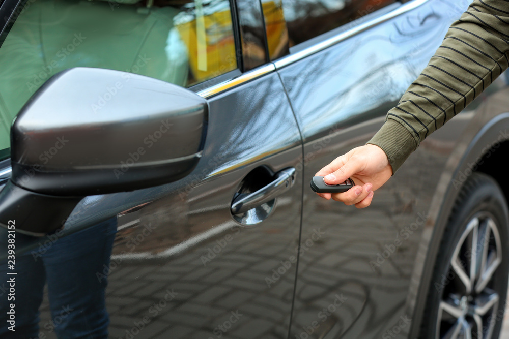 Closeup view of man opening car door with remote key