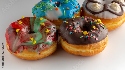 Fresh colorful donuts topped with glaze and decorated with colorful decorations on a white background