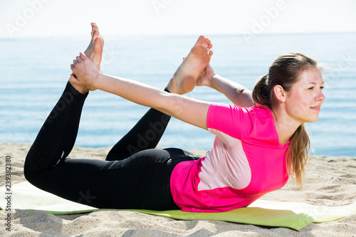 Woman training yoga poses on beach