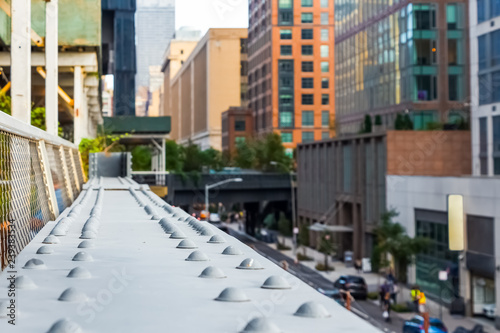View of the railings on The High Line with blurry Manhattan street and buildings  in the background, New York, USA