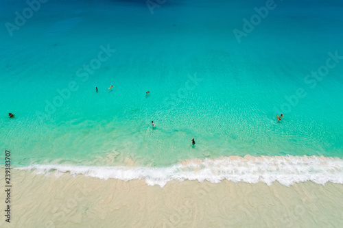 Aerial view of sandy beach with tourists swimming in beautiful clear sea water