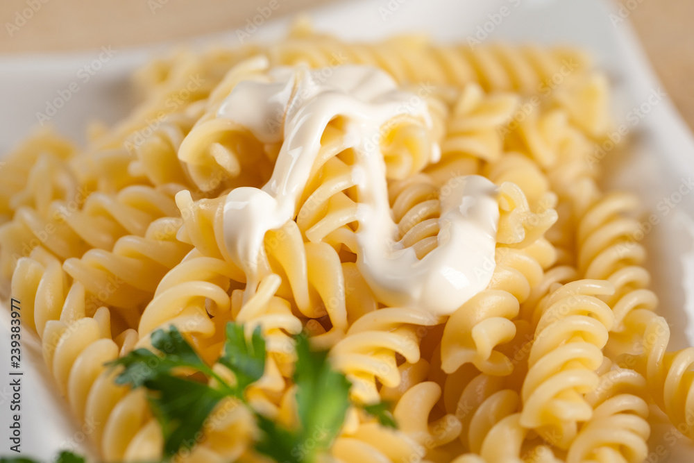 Pasta in white plate, parsley, bowl with mayonnaise sauce Pasta in white plate, parsley, bowl with mayonnaise sauce