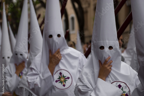 Foto Hooded dressed in white in procession, hold the hood against the wind