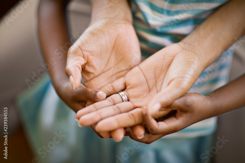 Hands of a mid-adult woman on top of a young girls hands.