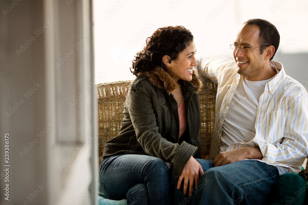 Happy mid adult couple sitting on a front porch. Happy mid adult couple sitting on a front porch.