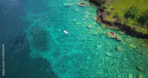 Aerial drone view of woman doing Stand up paddleboard in tropical clear waters a the Caribbean Island