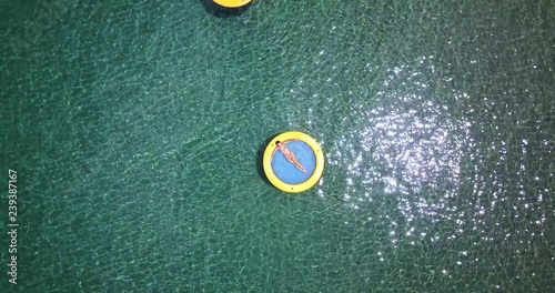 Drone over a girl in bikini relaxing on a water hammock on a Tropical paradise beach setting in the Caribbean island of St Lucia