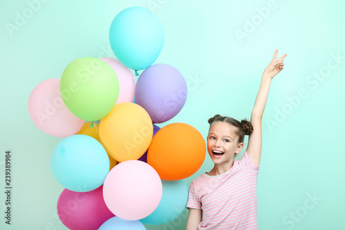 Beautiful young girl with colored balloons on mint background