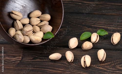 Pistachios in a plate on a wooden background