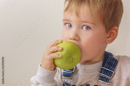 Boy bites a green apple