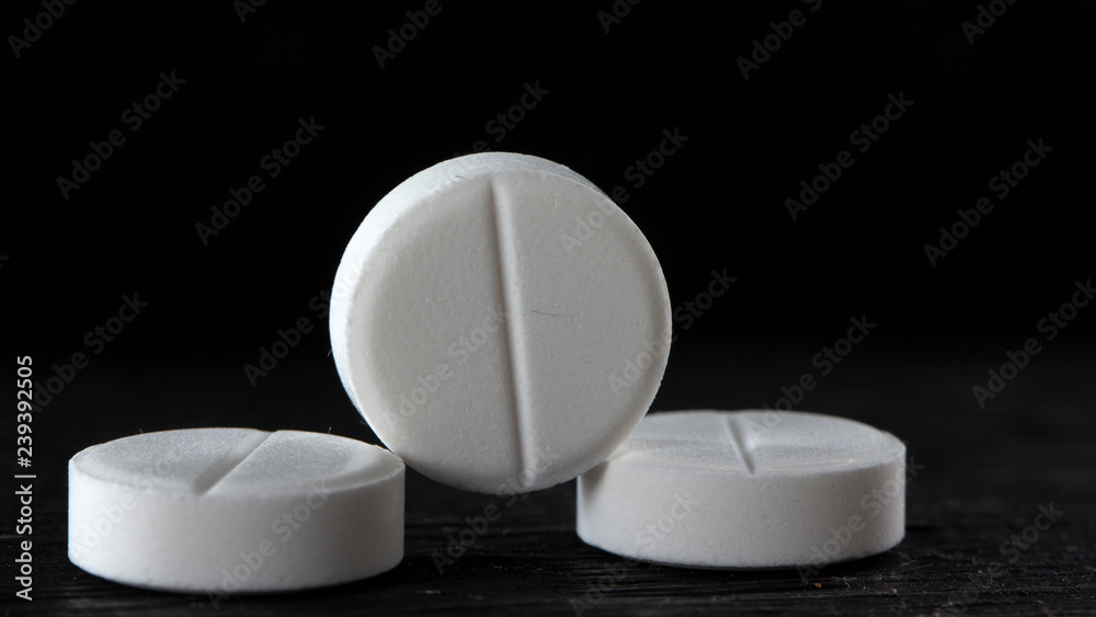 Three white pill on black background close up Three white pill on black background close up