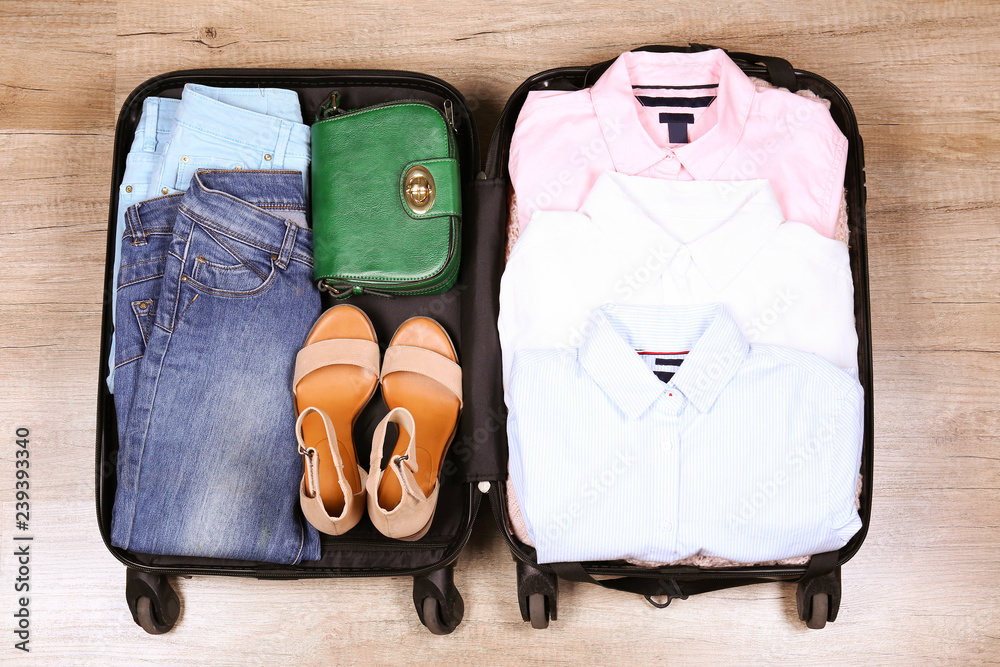 Open suitcase fully packed with folded women s clothing and