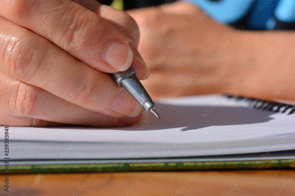 Woman, pen in hand, writing in a notebook Woman, pen in hand, writing in a notebook