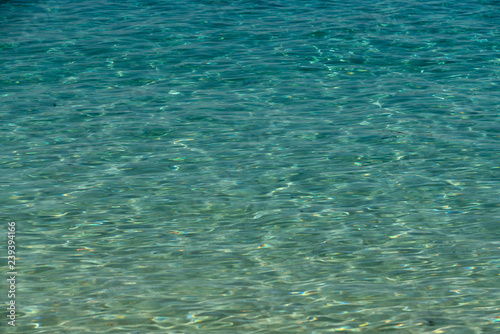 The clear water of the tropical sea shimmers under sunlight of emerald color.