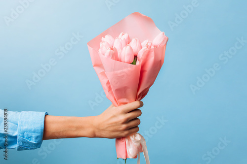 Fototapeta Naklejka Na Ścianę i Meble -  flowers in the hands of a man for Valentine's Day, on a blue background