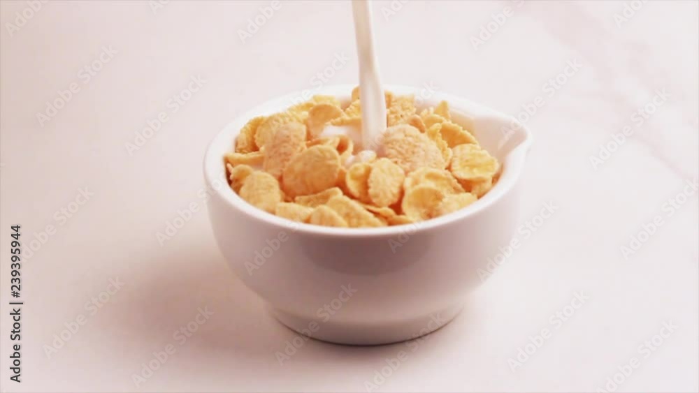 Crunchy corn flakes in bowl with fresh milk on light marble background. Horizontal view Crunchy corn flakes in bowl with fresh milk on light marble background. Horizontal view