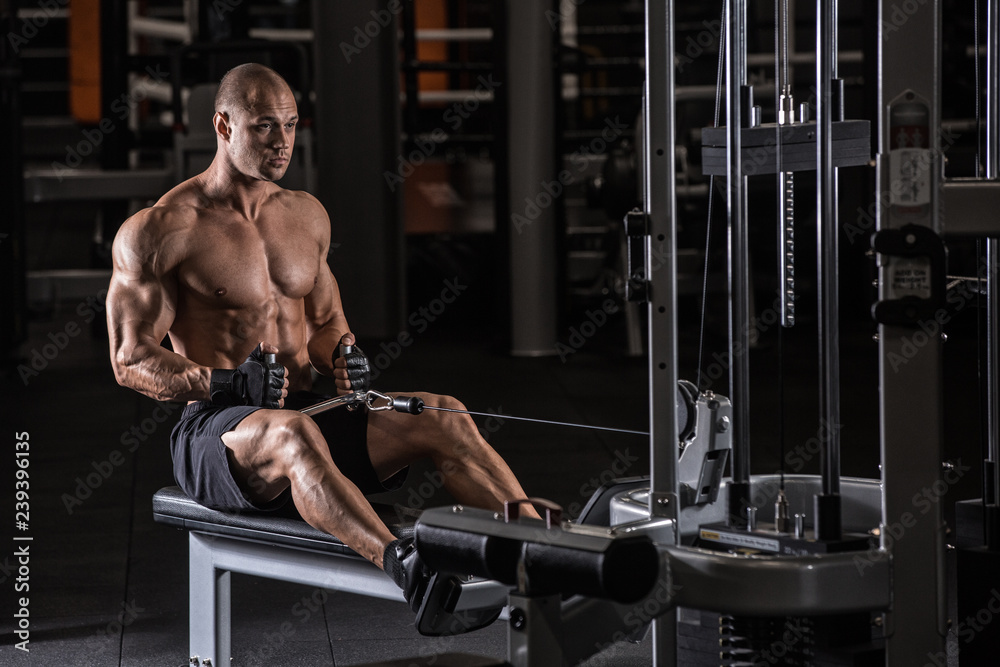 Naklejka premium Brutal strong bodybuilder athletic man pumping up muscles workout bodybuilding concept background