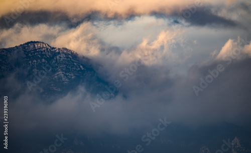 Beautiful view of some snowy mountains surrounded by soft clouds during sunset in Italy.