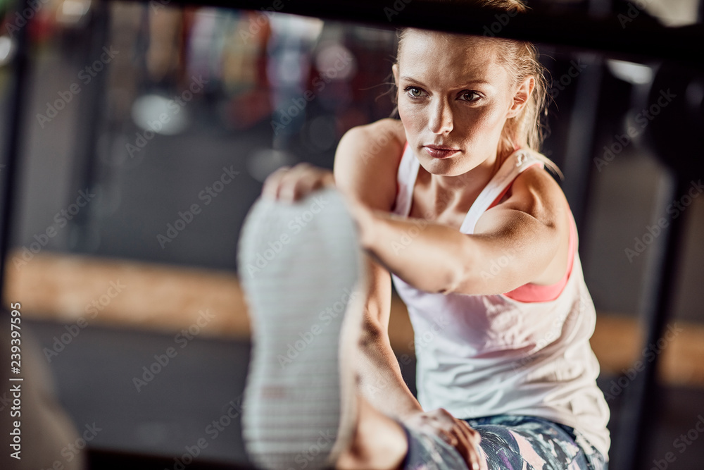 fit blonde female stretching her leg in a fitness studio