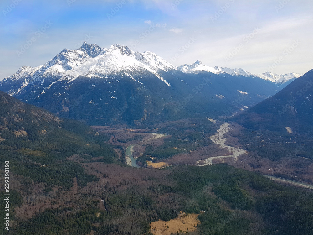 AERIAL: Flying over vast forest and towards the snowy mountains in Bella Coola.