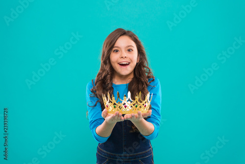 My biggest treasure. Kid hold golden crown symbol of princess. Childhood concept. Every girl dreaming to become princess. Lady little princess. Girl cute baby hold crown while stand blue background