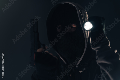 Armed burglar intruder with flashlight torch at night