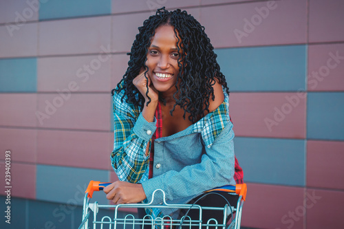 Young beautiful woman dressed in casual clothes with a shopping cart near the mall