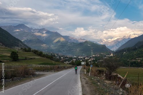 Tourist walking on a road to Mestia with Tetnuldi mountain on background