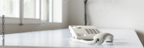 Wide view image of white landline telephone with handset off line