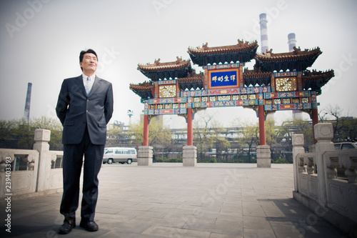 Asian businessman in front of an ornate Chinese gate. photo
