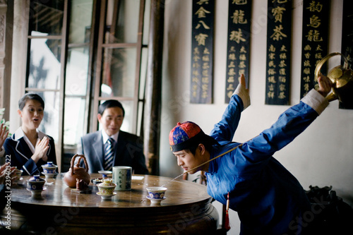 Young adult man dressed in traditional clothing doing a tea ritual in a cafe.