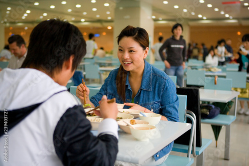 Teenage girl sitting with a friend eating lunch.