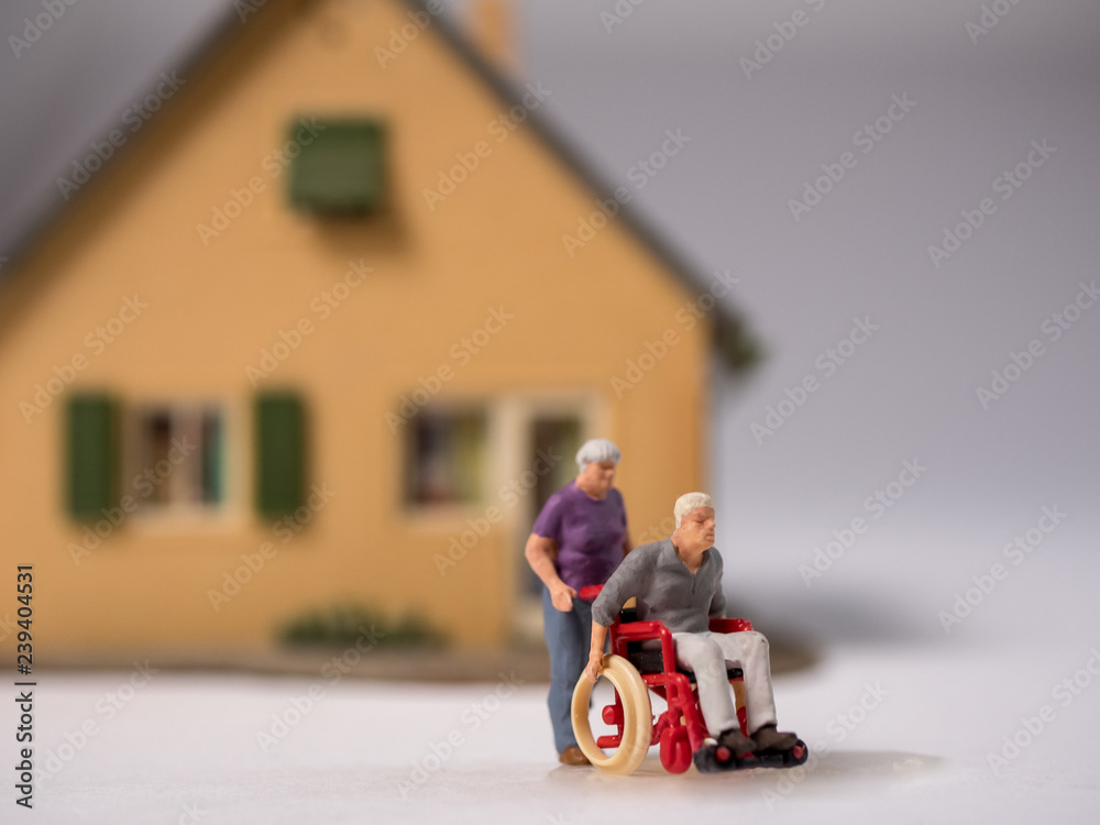 Senior im Rollstuhl und Pflegekraft vor Privathaus