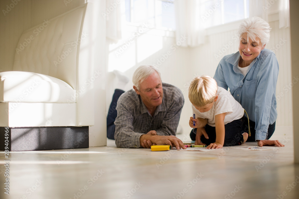 Young boy sitting on the floor with his grandparents and drawing with crayons. Young boy sitting on the floor with his grandparents and drawing with crayons.