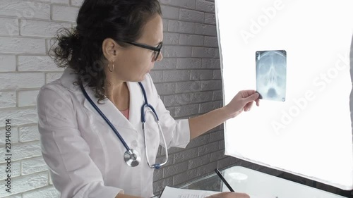 Doctor examines x-ray through negatoscope. Female doctor with x-ray of a human skull. photo