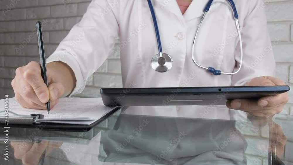 Doctor using digital tablet. The doctor fills out electronic and paper documents. Doctor using digital tablet. The doctor fills out electronic and paper documents.