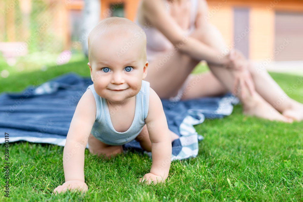 Portrait of cute little caucasian boy having fun in garden with mother. Child crawling on green grass lawn during walk with mom in yard. Happy childhood and baby healthcare Portrait of cute little caucasian boy having fun in garden with mother. Child crawling on green grass lawn during walk with mom in yard. Happy childhood and baby healthcare