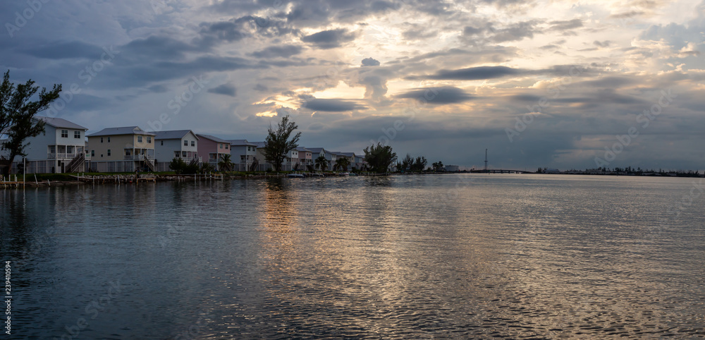 Panoramic view of residential homes on the ocean shore during a vibrant cloudy sunset. Taken in Key West, Florida Keys, United States.