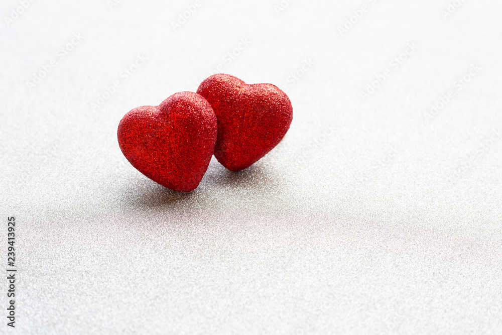 Fototapeta premium The red heart shapes on silver glitter paper background in love concept for valentines day.