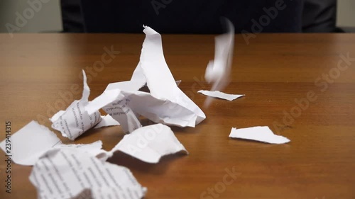 Torn pieces of paper fall on the table.