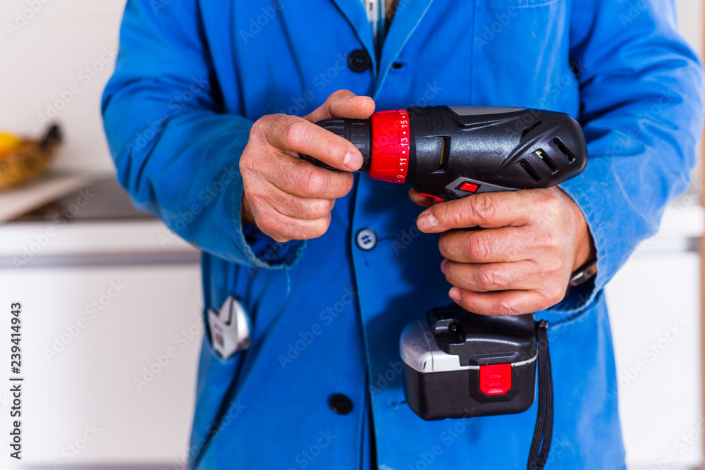 Workman holding power drill in kitchen Workman holding power drill in kitchen