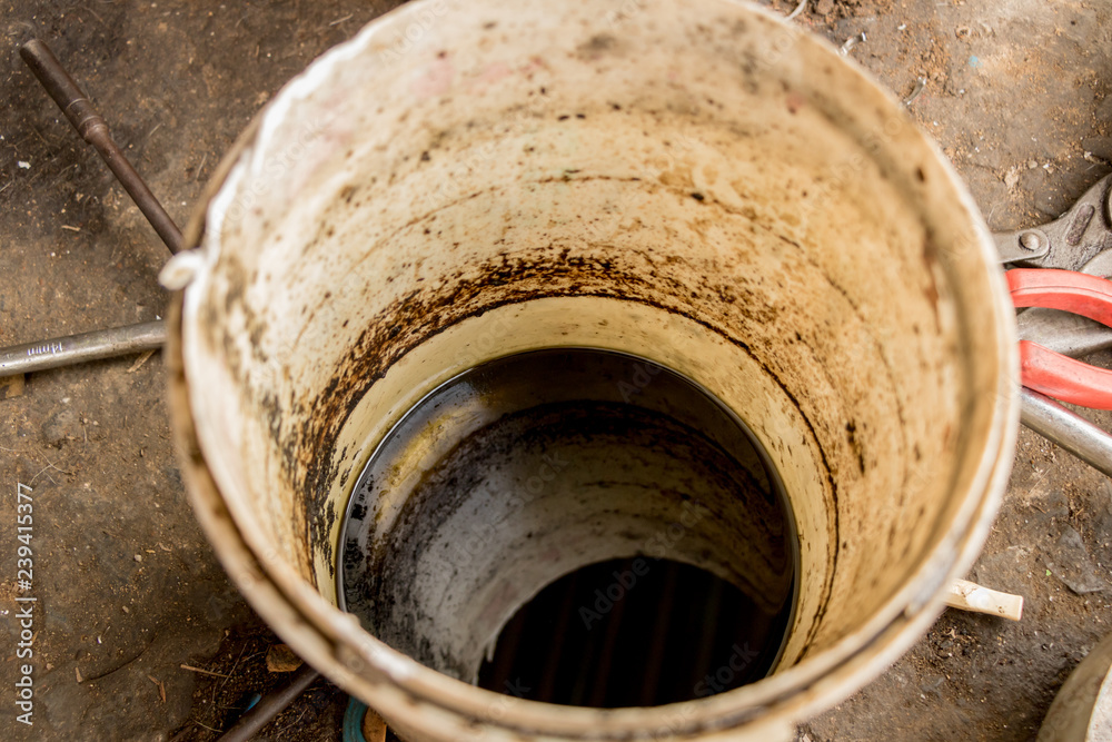 Used Oil/ Dirty Black Liquid in White Bucket - Concrete Ground - Recycle - Environmental Friendly Used Oil/ Dirty Black Liquid in White Bucket - Concrete Ground - Recycle - Environmental Friendly