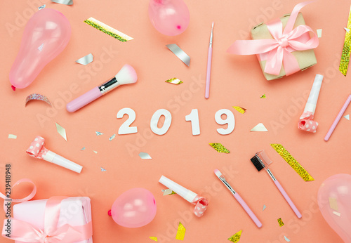 Table top view of Merry Christmas decorations & Happy new year 2019 ornaments concept.Flat lay essential difference objects gift box & text with golden confetti on modern pink paper background.
