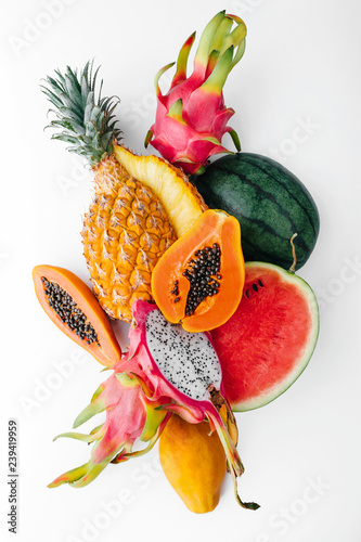 Flat lay tropical fruit layout made of dragon fruit, watermelon, papaya and pineapple on a white background, creative summer food concept