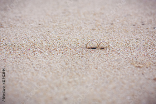 Two wedding gold rings in the sand on the background of beach