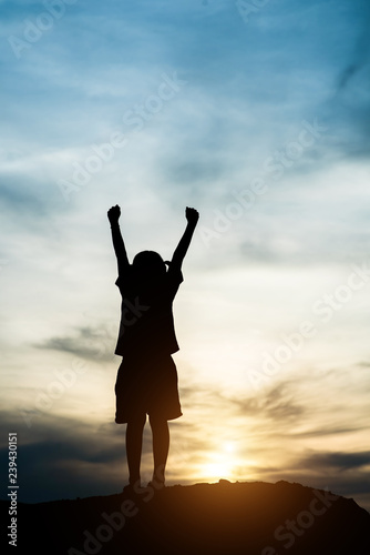 Silhouette of little girl raising hand to freedom happy time