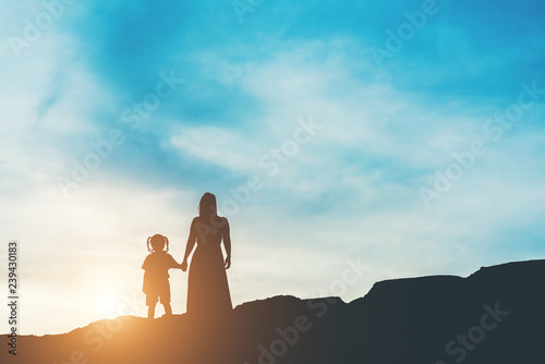 Silhouette of mother with her daughter standing and sunset