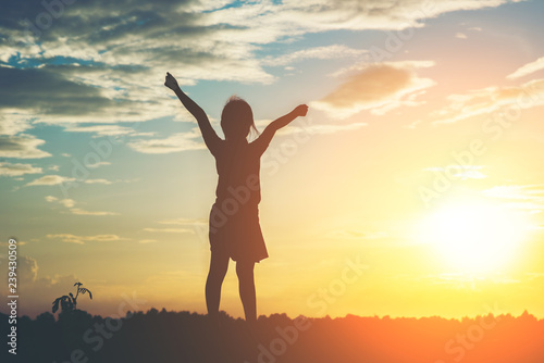 Silhouette of little girl raising hand to freedom happy time