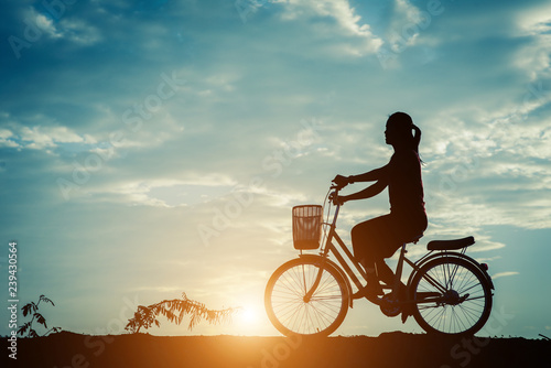 Silhouette of women with bicycle and beautiful sky