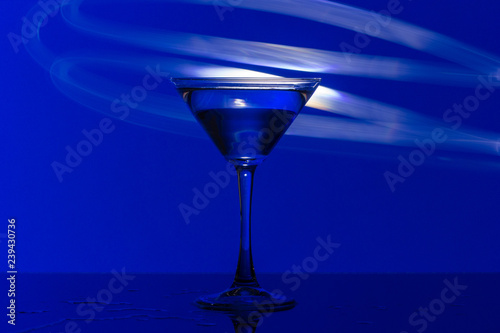 Martini glass on blue background and bright club lights.